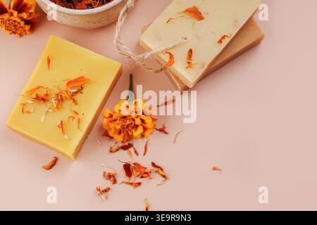 Natürliche Seifenstangen und Ringelblumenblätter auf rosa Hintergrund Stockfoto