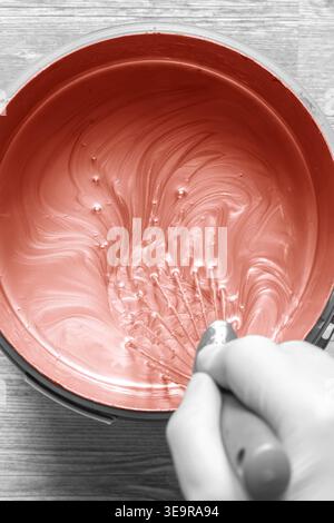 Person, die Kupferfarbe in einem Kunststoffbehälter mit einem Metallquirl mischt. Dekorationskonzept Do IT Yourself für Zuhause. Stockfoto