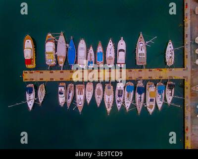 Von oben aus der Drohne aus der Vogelperspektive auf Segelboote und Motorboote, die an einem Yachthafen-Pier in Griechenland vor Anker liegen Stockfoto
