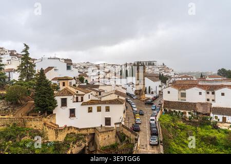 Ein großer Panoramablick auf Ronda in Andalusien. Das Bild zeigt die typischen weiß getünchten Häuser auf dem Hügel, die historische Kirche Padre Jesús aus Stein Stockfoto