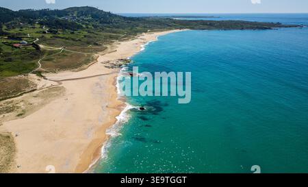 Ein atemberaubender Blick aus der Luft fängt die unberührte Schönheit von Praia de Espiñeirido in Galicien ein. Ein langer Holzsteg schlängelt sich durch Sanddünen in Richtung Stockfoto
