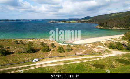 Diese Luftaufnahme zeigt einen weißen Wohnwagen, der in der Nähe von Lago Beach in Merexo geparkt ist. Die Landschaft zeigt die Mündung des Lago River, die in den Atlantik mündet, Stockfoto