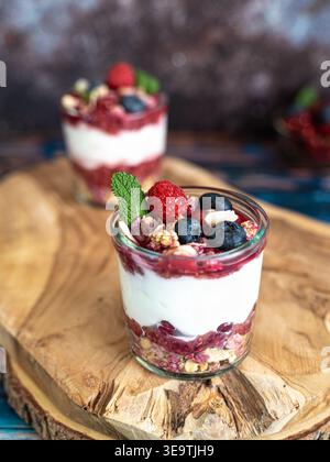 Nahansicht des mehrschichtigen Beerenparfaits mit Creme Minze und Müsli auf Holzscheibe Stockfoto