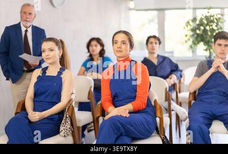 Junge Studenten in blauen Overalls, die an einem technischen Seminar teilnehmen Stockfoto