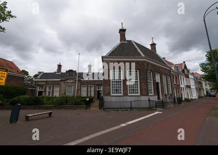 Historisches Hofje-Torhaus mit Ziegelfassade und markanten Kuppeln mit Blick auf den Innenhof unter bewölktem Himmel in Haarlem, Niederlande. Stockfoto