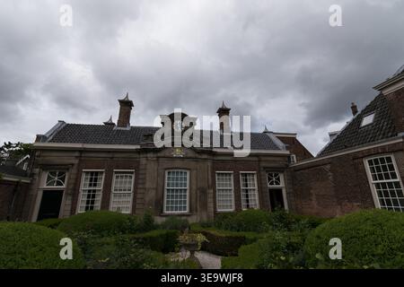 Herrenhaus aus der Barockzeit mit formellem Gartenhof unter dramatischem Sturmhimmel in Haarlem, Niederlande. Symmetrische Fassade mit Uhrenturm und Maniküre Stockfoto