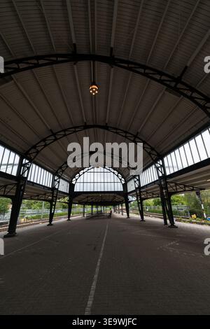 Leerer Bahnsteig unter dem bogenförmigen Dach des viktorianischen Bahnhofs Haarlem, Niederlande. Symmetrische Metallstruktur mit geometrischem Design. Stockfoto