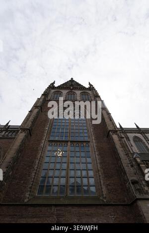 Westfassade der Kirche Grote Kerk (St. Bavo) aus einem niedrigen Winkel gegen den bewölkten Himmel in Haarlem, Niederlande. Gotische Architektur mit großem Tracery W Stockfoto