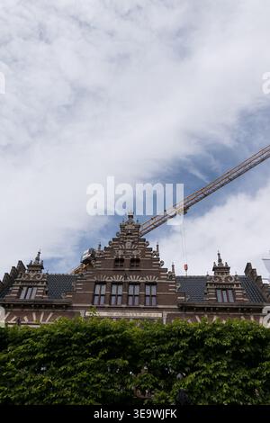 1902 niederländische Renaissance Stufengiebelfassade mit Baukran unter dramatischem bewölktem Himmel in Haarlem, Niederlande. Stockfoto