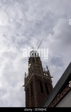 Flacher Blick auf den historischen gotischen Kirchturm mit Zifferblatt und verziertem Turm vor bewölktem Himmel in Haarlem, Niederlande. Stockfoto