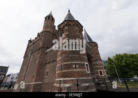 Amsterdamse Poort, ein mittelalterliches Stadttor mit zwei Backsteintürmen und konischen Dächern, fotografiert aus einem niedrigen Winkel vor stürmischem Himmel in Haarlem, Niederlande Stockfoto