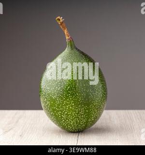 Unreife grüne Passionsfrucht auf einem Holztisch - Passiflora ligularis Stockfoto