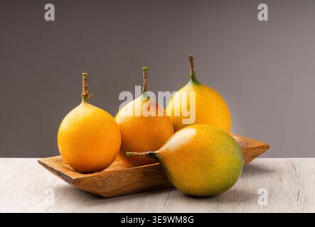 Vier reife Granadillas auf einem Holztablett - Passiflora ligularis Stockfoto