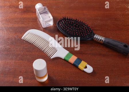Arrangement mit zwei Kämmen, einer schwarzen Haarbürste und zwei kleinen Flaschen auf Holzoberfläche. Konzentrieren Sie sich auf Haarpflege für Wellness, Hygiene und persönliche Zwecke Stockfoto