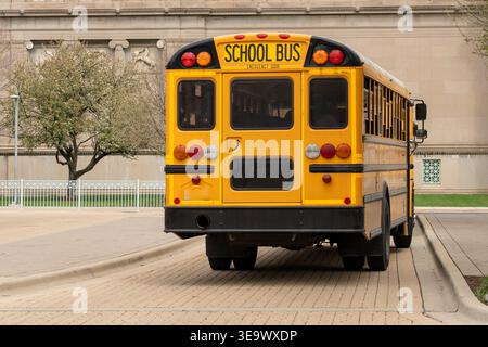 Hellgelber Schulbus, der eine ruhige Straße in den USA entlang fährt, bereit, Schüler abzuholen. Ein klassisches Symbol für Bildung und Kindheitserlebnisse Stockfoto