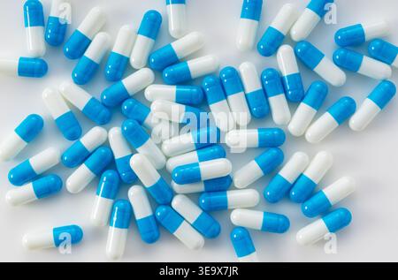 Voller Rahmen von blauen und weißen Kapseln, verstreut auf weißem Hintergrund, medizinisches und pharmazeutisches Konzept von oben Stockfoto