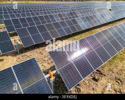 Moderne Photovoltaik-Module, die auf bodenmontierten Regalsystemen auf einer Baustelle eines Solarkraftwerks installiert sind, die für eine nachhaltige saubere Elektroenergie ausgelegt sind Stockfoto