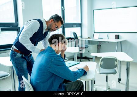 Der Lehrer unterstützt den Lernenden mit Lernschwierigkeiten während des Unterrichts. Stockfoto