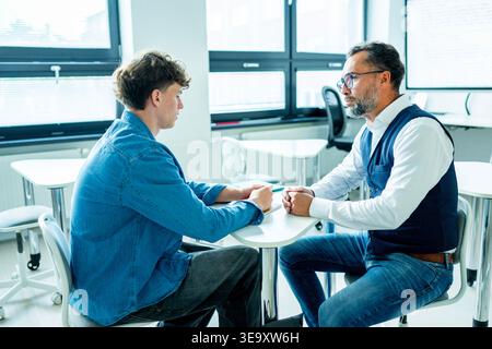 Lehrer, der sich um einen schwer wiegenden Schüler kümmert. Junge, der sich einem Lehrer anvertraut. Stockfoto
