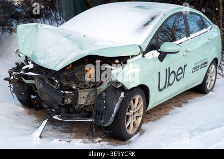 Kiew, Ukraine. Januar 2024. Das Auto des Uber-Taxis wurde nach einem Zusammenstoß auf einem Parkplatz zerstört. Kaputtes Auto nach einem Unfall im Winter Stockfoto