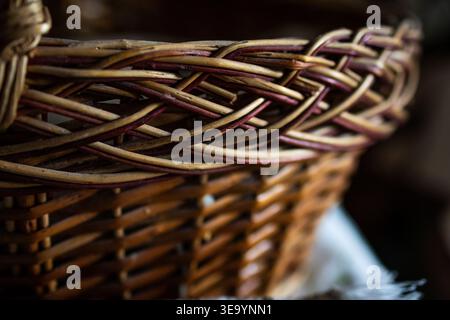 Detaillierter Blick auf einen gewebten Korb mit verzierten geflochtenen Kanten und Erdtönen. Der flache Fokus hebt die taktilen Fasern und die traditionelle Handwerkskunst hervor Stockfoto