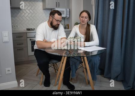 Verheiratete Paare sitzen an einem Tisch in ihrer Küche, kalkulieren das Familienbudget, verwalten Geld und planen Ausgaben, während sie Bankrott halten Stockfoto