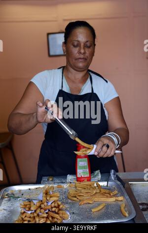 Eine Kubanerin, die Churros in einem kleinen Laden auf der Simón Bolívar Avenue in Havanna, Kuba, zubereitet. Stockfoto