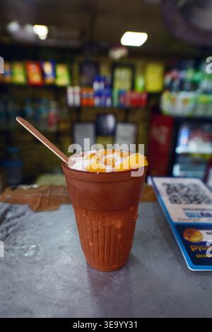 Eine traditionelle Tontasse Mango Lassi serviert in einem berühmten Lassi-Shop auf der Baba Kharak Singh Rd bei den Hindu-Tempeln in Neu-Delhi, Indien. Stockfoto