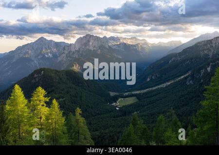 Aus der Vogelperspektive auf die dramatische, sonnenverwöhnte Mangart Bergkette und das üppige grüne Tal darunter schaffen eine atemberaubende Landschaft, Log Pod Mangartom, BOV Stockfoto