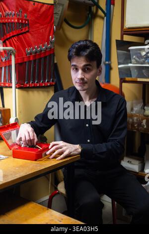 Porträt eines jungen Technikers, der auf einem Werkstatttisch arbeitet Stockfoto