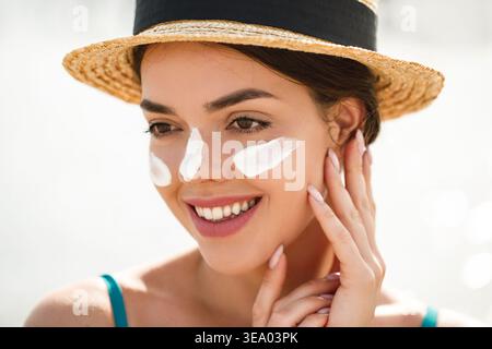 Porträt der schönen jungen Frau mit sauberer, frischer Haut, die das Gesicht berührt. Sonnencreme. Sonnenschutz. Sonnencreme. Haut- und Körperpflege. Gesichtsbehandlung Stockfoto