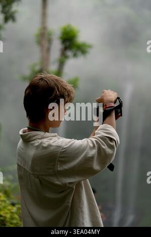 Junge Frau fotografiert den nebeligen Wasserfall im Dschungel, Bali Stockfoto