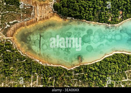 Aus der Vogelperspektive auf das pulsierende türkisfarbene Wasser trifft auf die üppig grünen Wälder, eingerahmt von der zerklüfteten Küste, Omiš, Kreis Split-Dalmatien, Kroatien. Stockfoto
