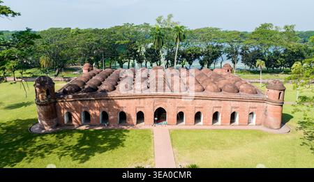 Aus der Vogelperspektive des roten Ziegelsteins der Sixty Dome Moschee im Kontrast zum üppigen grünen Rasen unter dem hellen Himmel, Bagerhat, Khulna Division, Bangladesch. Stockfoto