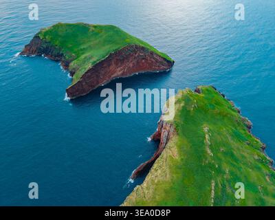 Aus der Vogelperspektive des markanten Kontrastes von grüner Vegetation und rotem vulkanischem Gestein auf den Inseln Ilhéus das Cabras gegenüber dem tiefblauen Meer Ilhéus das Stockfoto