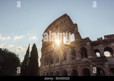 Sonnenschein durch die Bögen des Kolosseums in Rom mit historischer Fassade und klarem blauem Himmel Stockfoto