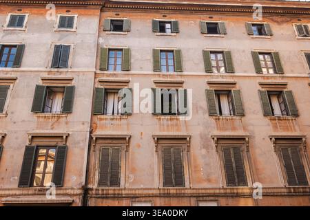 Historische Wohnfassade mit verschlossenen Fenstern und veralteten Putzwänden in Rom Stockfoto