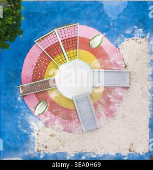Aus der Vogelperspektive auf einen Spielplatz mit Rutschen, Kletternetzen und einem Sandkasten mit lebhaften Kreismustern und einer blauen Oberfläche in Taiwan. Stockfoto
