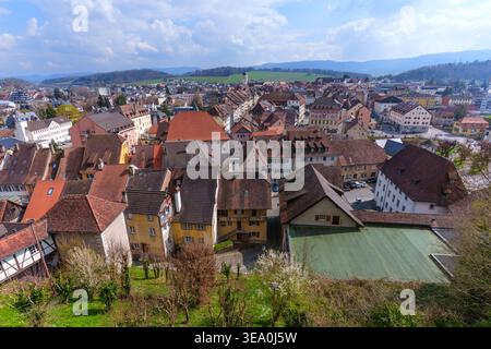 Der Blick aus der Höhe zeigt die roten Dächer der mittelalterlichen Stadt Porrentruy, eingebettet in die sanften grünen Hügel des Juras unter einem hellblauen Himmel i Stockfoto