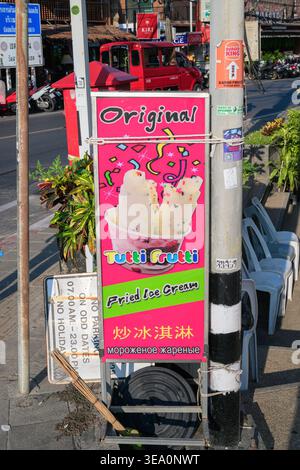 Ein hochdetailliertes, vertikales Straßenfoto zeigt ein leuchtendes rosafarbenes Werbeschild „Original Tutti Frutti Fried Ice Cream“ in Karon, Phuket, Thailan Stockfoto