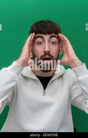Junger Mann, der überraschend reagiert und den Kopf hält Stockfoto