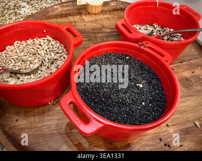 Verschiedene Samen in roten Schalen auf Holztablett, Konzept der Bäckerei, gesunde Lebensmittel, Banner Stockfoto