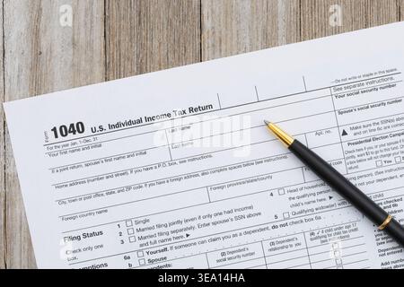 US 1040 Einkommensteuererklärung mit Stift auf hölzernem Schreibtischhintergrund, der Steueranmeldung, Buchhaltung und Finanzdokumentation darstellt. Stockfoto