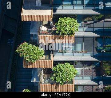 Blick aus der Vogelperspektive auf ein modernes Wohngebäude mit Holzbalkonen mit üppig grünen Bäumen und Glasfenstern in Taiwan. Stockfoto