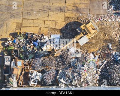 Luftaufnahme einer Ressourcenrückgewinnungsanlage mit einem Bagger, der Schrottstapel und industrielle Abfälle in Taiwan bewegt. Stockfoto