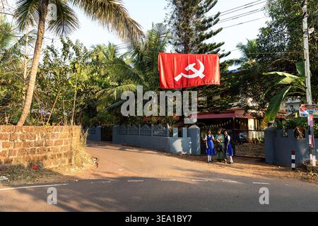 Kommunistische Symbole auf den Straßen Kannur City in Kerala in Indien, Hammer und Sickle auf einer roten Flagge, Fahnen hängen über den Straßen, Einheimische an der Bushaltestelle Stockfoto