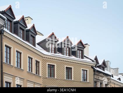 Altstadtarchitektur in Lublin mit schneebedeckten Dächern. Eine Reihe von farbenfrohen historischen Gebäuden mit traditionellen Dachfenstern, die mit Schnee bedeckt sind. Stockfoto