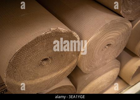 Gewalzte Wellpappenfolien, im Lagerlager gestapelt, Verpackungsmaterialrollen. Konzept: Verwendung von Recyclingmaterialien Stockfoto