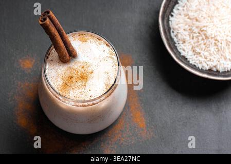 Mexikanische Horchata mit Zimt im Glas auf schwarzem Hintergrund, Kopierraum. Frisches hausgemachtes Horchata-Reisgetränk für ein erfrischendes, kaltes Sommerrezept. Stockfoto