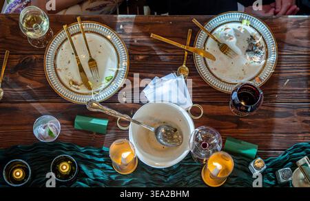 Blick aus einem hohen Winkel auf den eleganten Esstisch für einen Empfang, nachdem alles gegessen wurde, mit schmutzigem Geschirr. Stockfoto